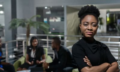 Black woman in office setting arms crossed looks as if she is achieving all her goals