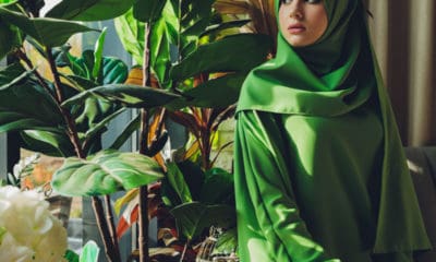 Woman in green hijab posing in front of tropical plants
