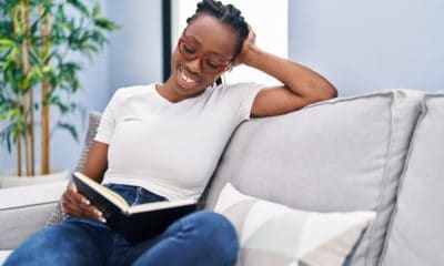 Woman sitting on couch reading something funny, laughing, quips and quotes